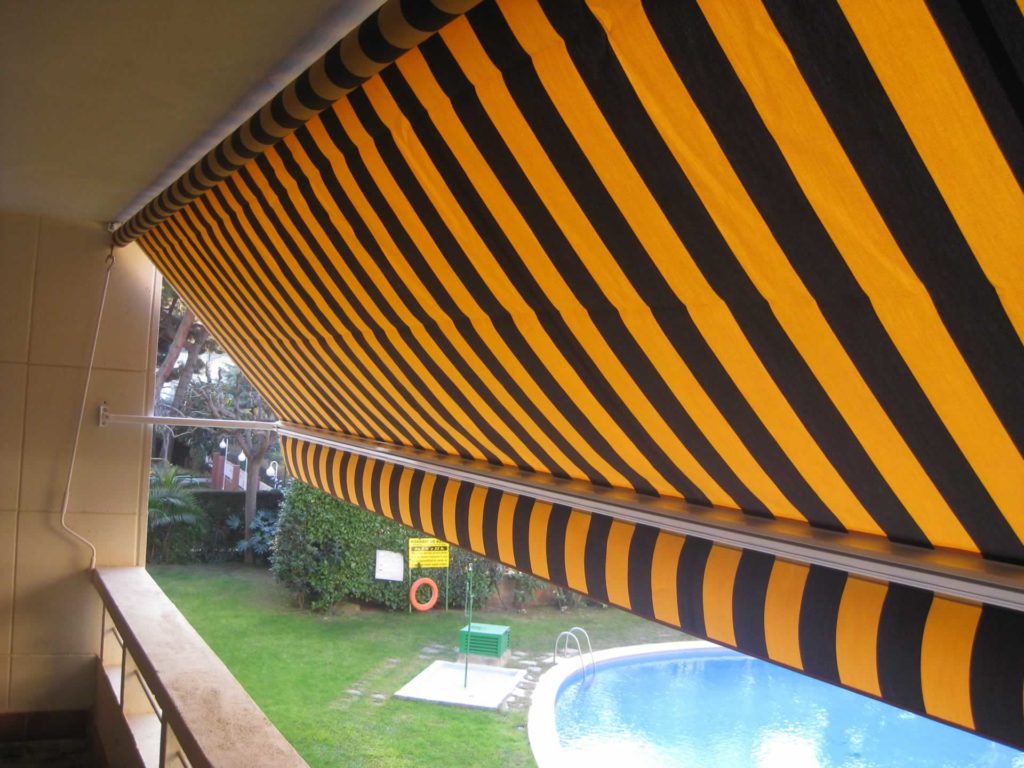 Toldo portada en balcón con vista de piscina
